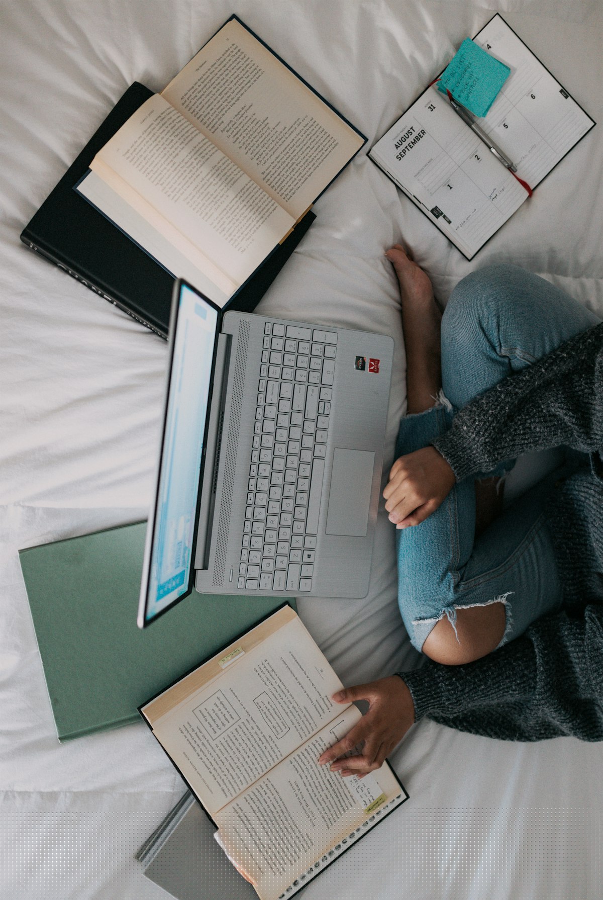 Student revising with books, a laptop and a planner